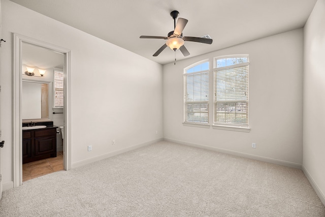 carpeted spare room featuring sink and ceiling fan