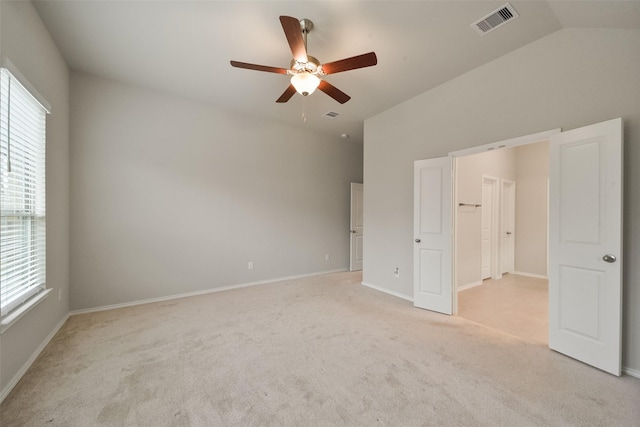 unfurnished bedroom with ceiling fan, light colored carpet, vaulted ceiling, and multiple windows