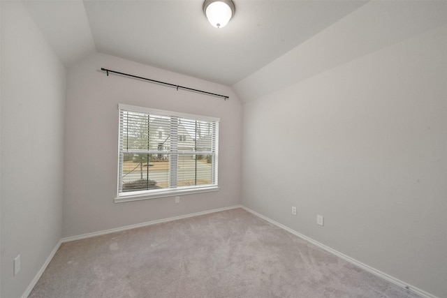 spare room with light colored carpet and vaulted ceiling