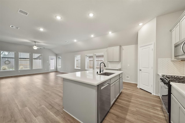 kitchen with tasteful backsplash, an island with sink, lofted ceiling, sink, and stainless steel appliances