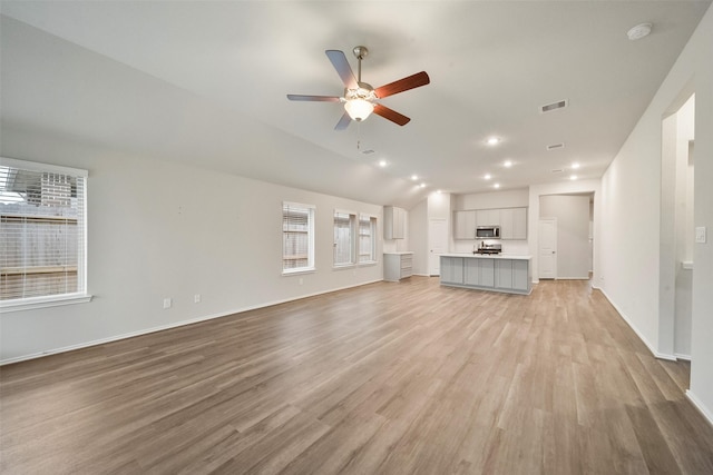 unfurnished living room with ceiling fan, vaulted ceiling, and light hardwood / wood-style flooring