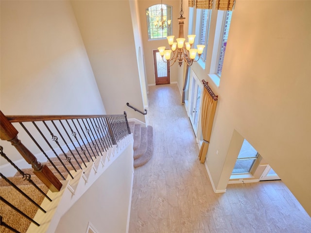 entrance foyer featuring a towering ceiling, a chandelier, and light hardwood / wood-style floors