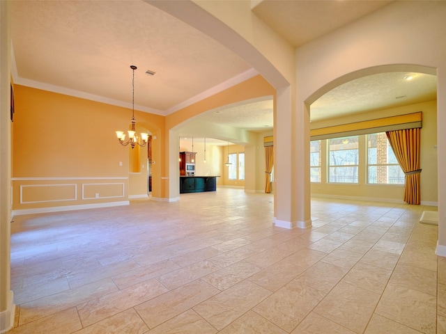 unfurnished living room featuring a notable chandelier, crown molding, and a wealth of natural light