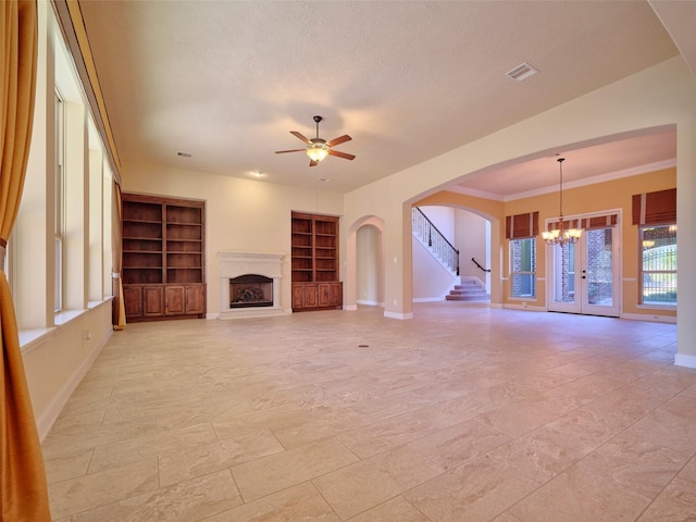 unfurnished living room featuring crown molding, ceiling fan with notable chandelier, a textured ceiling, and built in shelves