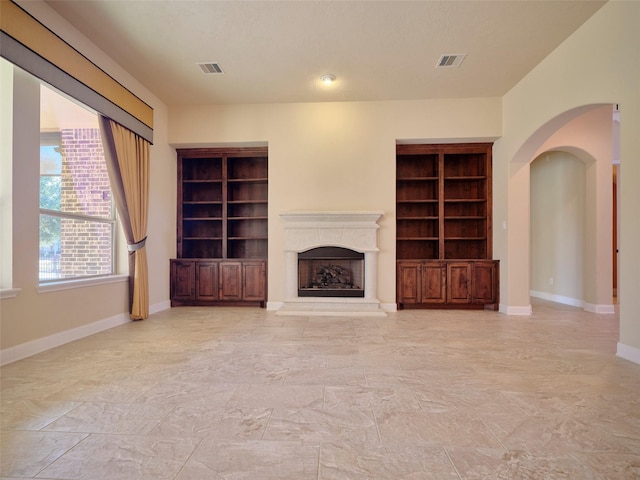 unfurnished living room with built in shelves