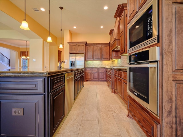 kitchen featuring tasteful backsplash, decorative light fixtures, a center island, appliances with stainless steel finishes, and dark stone counters