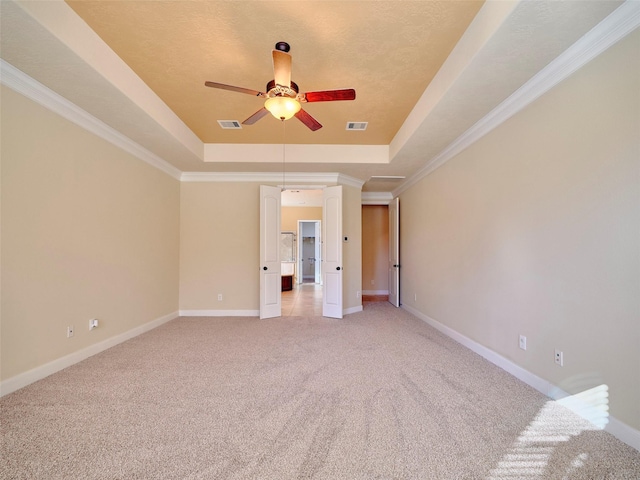 unfurnished bedroom featuring light carpet, a textured ceiling, ornamental molding, a raised ceiling, and ceiling fan