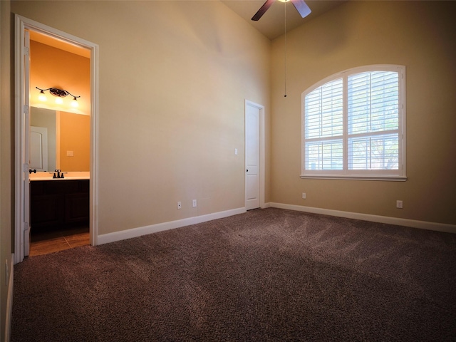 carpeted empty room with sink, high vaulted ceiling, and ceiling fan