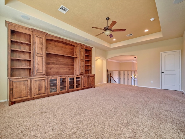 unfurnished living room featuring a textured ceiling, a raised ceiling, ceiling fan, and carpet