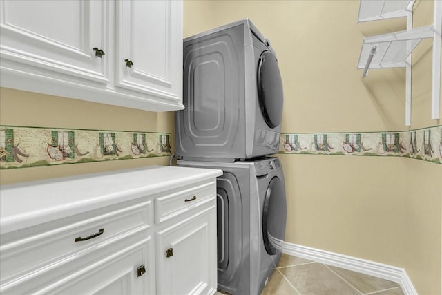 washroom with light tile patterned flooring, cabinets, and stacked washing maching and dryer