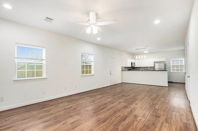 unfurnished living room featuring dark hardwood / wood-style flooring and ceiling fan