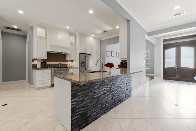 kitchen featuring sink, white cabinetry, high end appliances, dark stone countertops, and ornamental molding