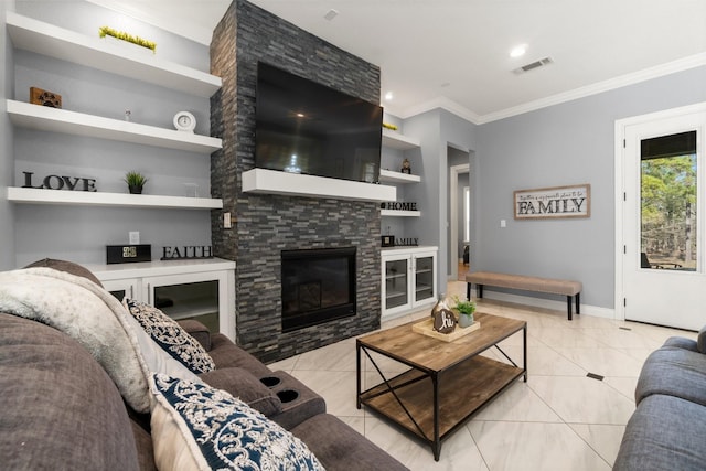 living room with light tile patterned floors, built in shelves, a stone fireplace, and ornamental molding