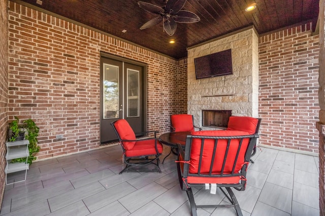 view of patio with an outdoor stone fireplace and ceiling fan