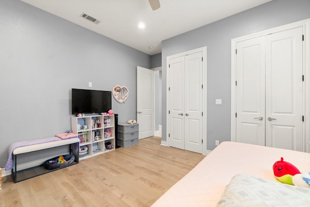 bedroom featuring hardwood / wood-style flooring, two closets, and ceiling fan