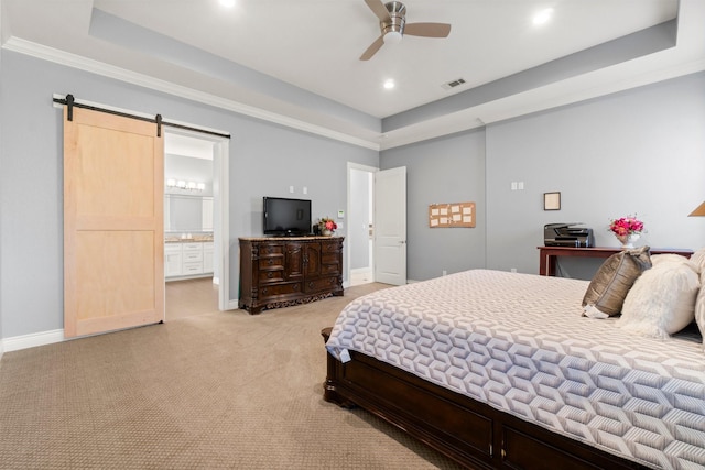 carpeted bedroom featuring a tray ceiling, a barn door, ceiling fan, and ensuite bathroom