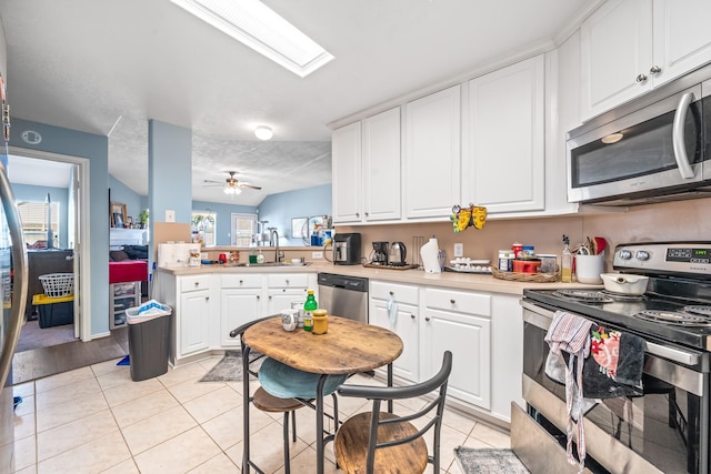 kitchen with white cabinetry, stainless steel appliances, light tile patterned flooring, and sink