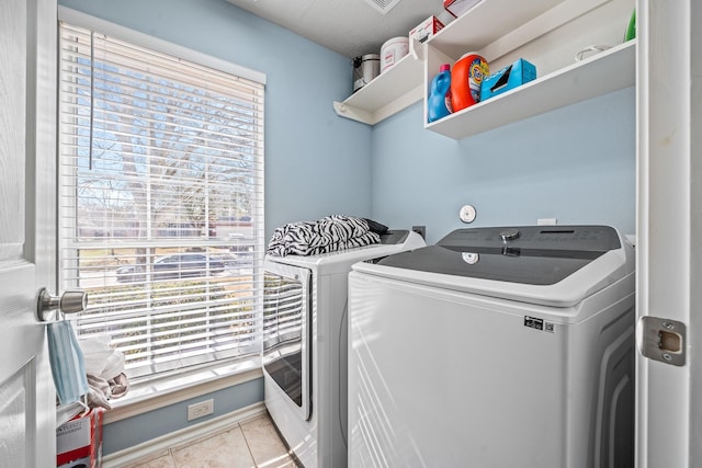 clothes washing area featuring light tile patterned flooring and washing machine and dryer