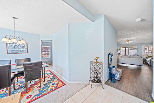 dining area with light tile patterned flooring, ceiling fan with notable chandelier, and a textured ceiling