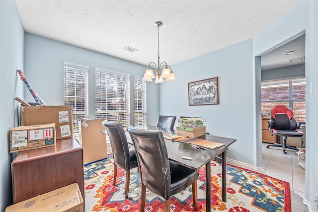 dining space with an inviting chandelier, light tile patterned floors, a healthy amount of sunlight, and a textured ceiling