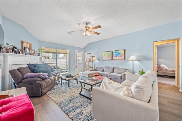 living room with hardwood / wood-style flooring, ceiling fan, lofted ceiling, and a textured ceiling