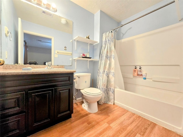 full bathroom with shower / tub combo, hardwood / wood-style floors, vanity, a textured ceiling, and toilet