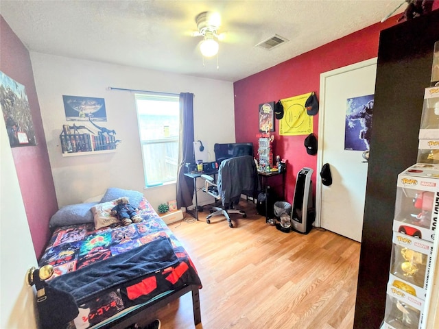 bedroom featuring hardwood / wood-style flooring, ceiling fan, and a textured ceiling