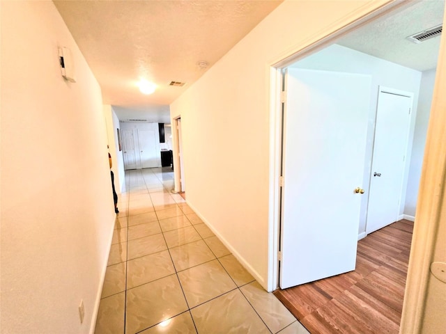 hall with light tile patterned floors and a textured ceiling