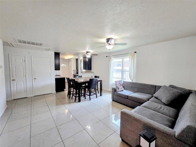 tiled living room featuring ceiling fan and a textured ceiling