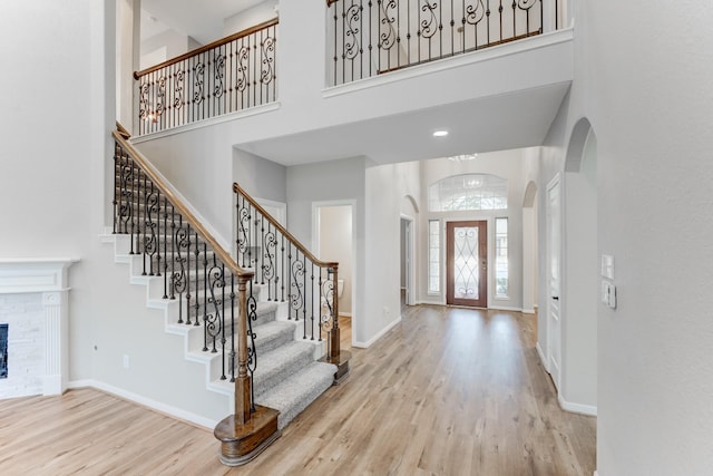 entrance foyer with a fireplace, light hardwood / wood-style flooring, and a high ceiling