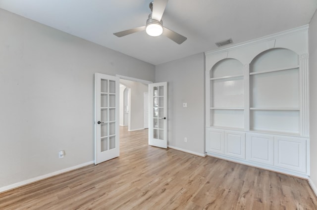 empty room featuring built in features, light hardwood / wood-style floors, french doors, and ceiling fan