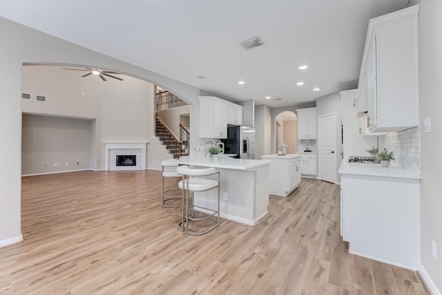 kitchen featuring a kitchen island, white cabinetry, a kitchen breakfast bar, stainless steel appliances, and light wood-type flooring