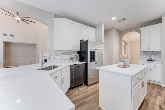 kitchen with appliances with stainless steel finishes, kitchen peninsula, sink, and white cabinets