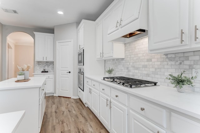 kitchen featuring stainless steel appliances, backsplash, white cabinets, and light hardwood / wood-style floors