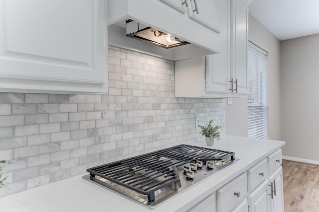 kitchen featuring white cabinetry, custom range hood, tasteful backsplash, and stainless steel gas cooktop