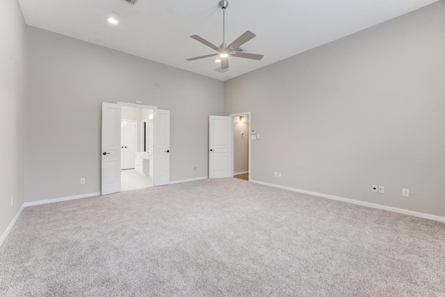 unfurnished bedroom with a high ceiling, ensuite bathroom, carpet floors, and ceiling fan