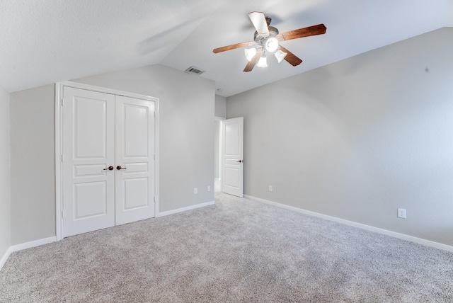 unfurnished bedroom featuring lofted ceiling, a closet, ceiling fan, and carpet flooring