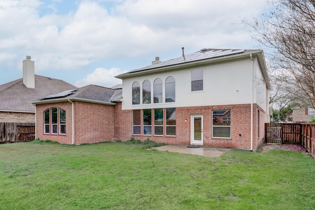 back of property featuring a lawn and solar panels