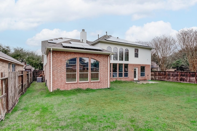 rear view of house featuring a yard and solar panels