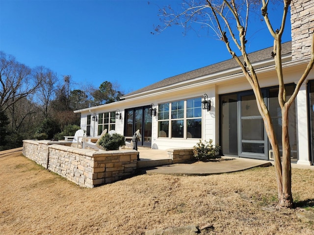 rear view of house with a patio and a lawn