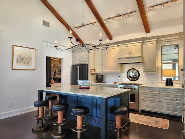 kitchen featuring decorative light fixtures, a center island, black refrigerator, stainless steel stove, and light stone countertops