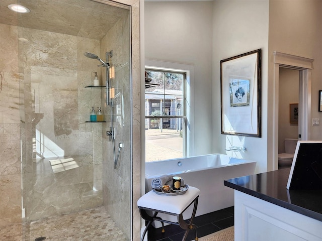 bathroom featuring toilet, tile patterned flooring, and a tile shower