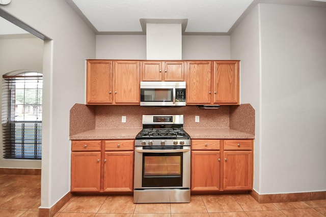 kitchen with stainless steel appliances, light tile patterned floors, and decorative backsplash