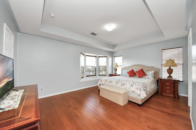 bedroom featuring a raised ceiling and dark hardwood / wood-style floors