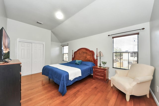 bedroom with hardwood / wood-style flooring, lofted ceiling, and a closet