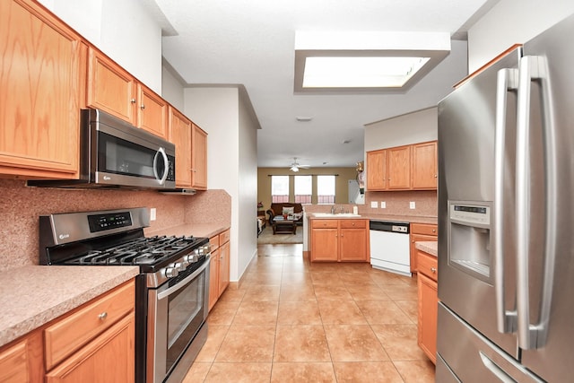 kitchen featuring appliances with stainless steel finishes, sink, decorative backsplash, light tile patterned floors, and kitchen peninsula