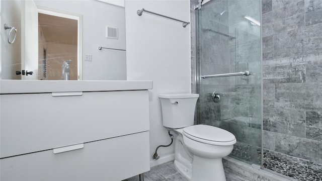 bathroom featuring a shower with door, vanity, and toilet