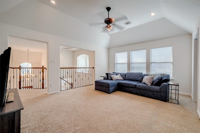 living room featuring ceiling fan with notable chandelier, vaulted ceiling, and carpet floors