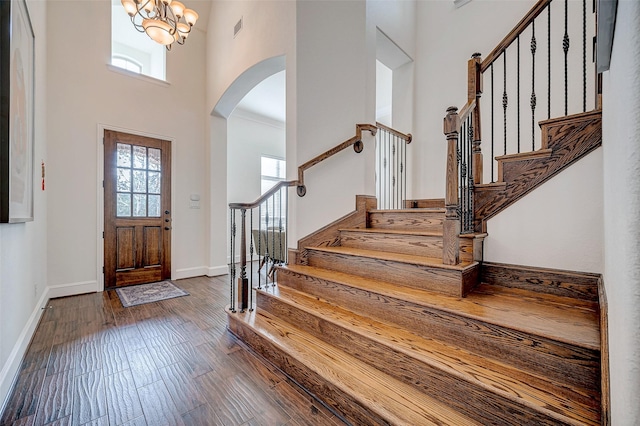 foyer with dark wood-type flooring, a high ceiling, and an inviting chandelier