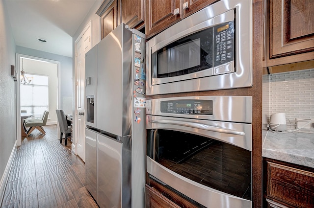 kitchen with appliances with stainless steel finishes, tasteful backsplash, and dark hardwood / wood-style floors